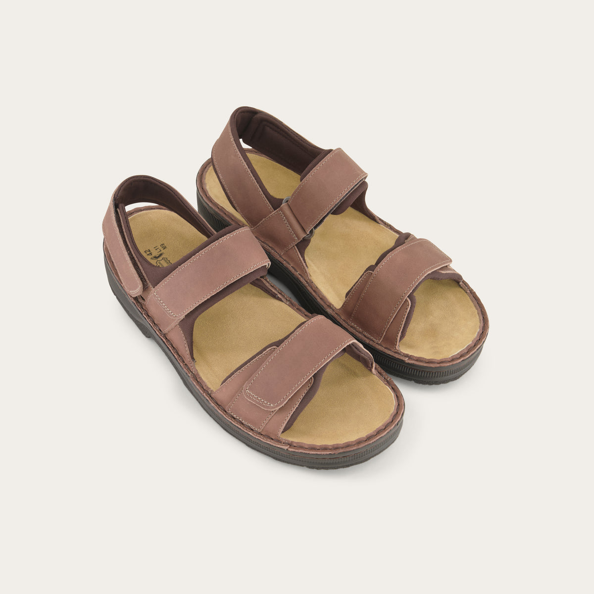 Pair of brown nubuck sandals featuring 3 hook and loop straps around the foot and ankle for adjustability on a black sole.