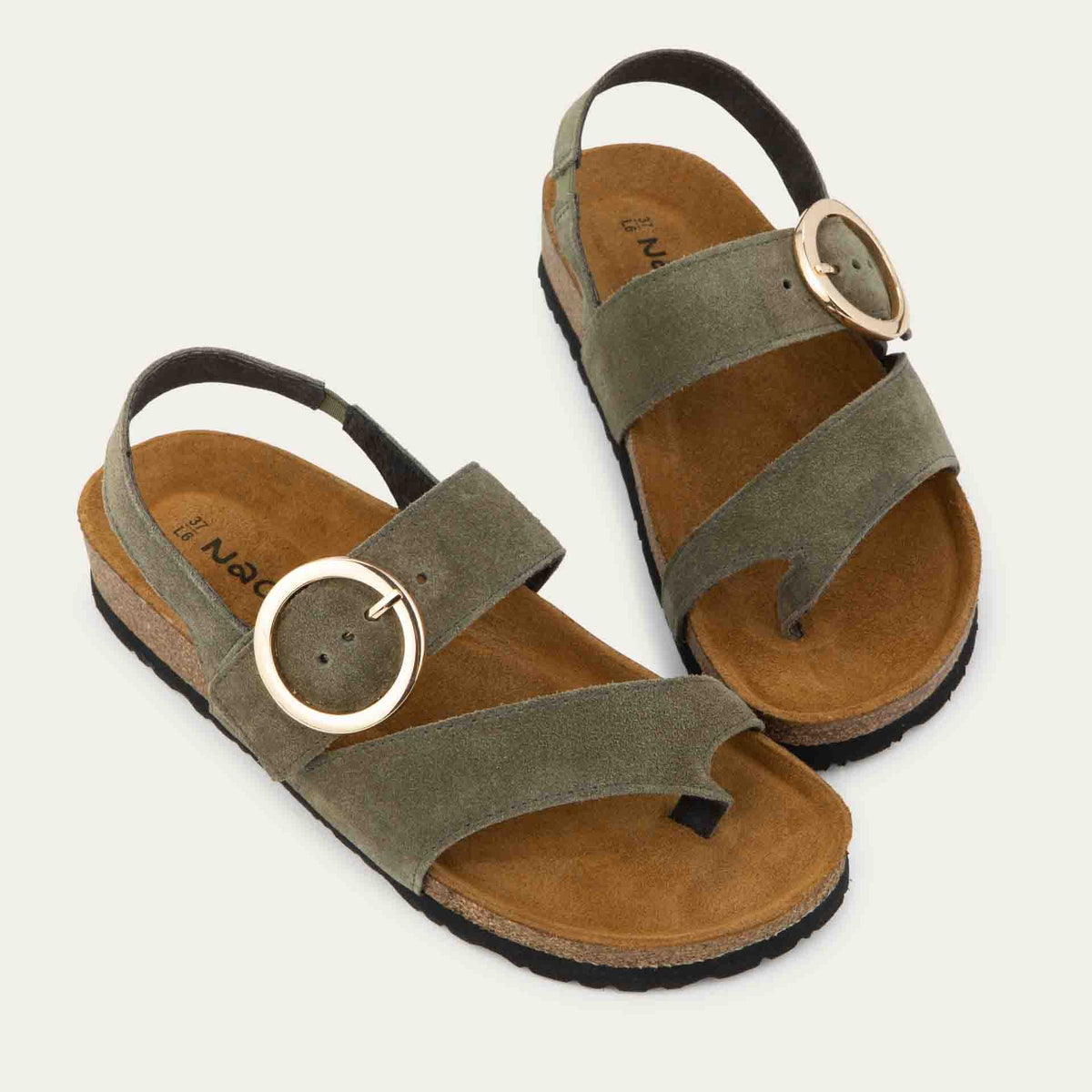 Pair of green strappy slides with an oversized buckle and a toe thong, featuring a cork sole.