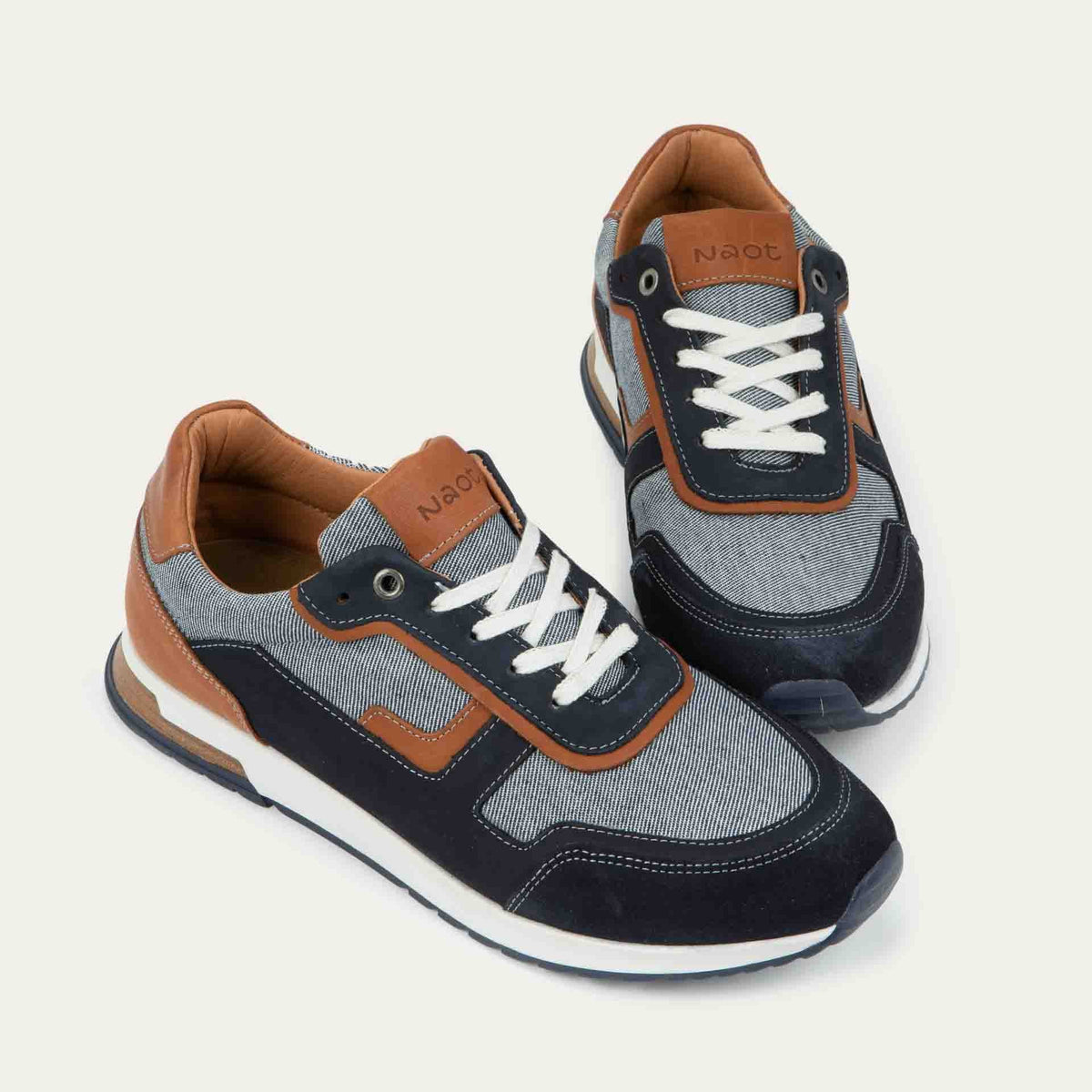 Pair of blue and brown sneakers featuring different materials on a white sole