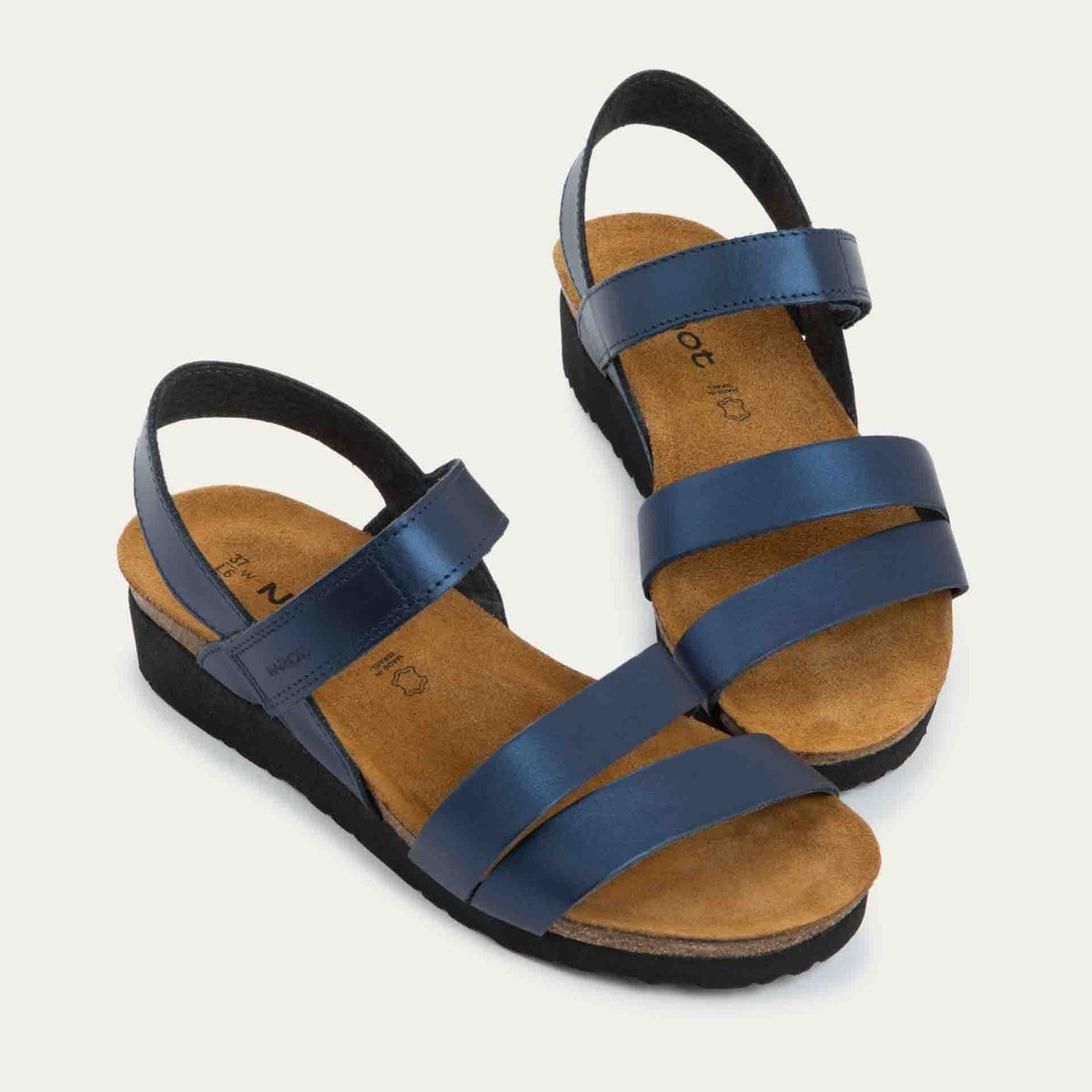 Pair of navy blue sandals with a cork footbed, black sole, and triple-strap design including a crisscross ankle strap.