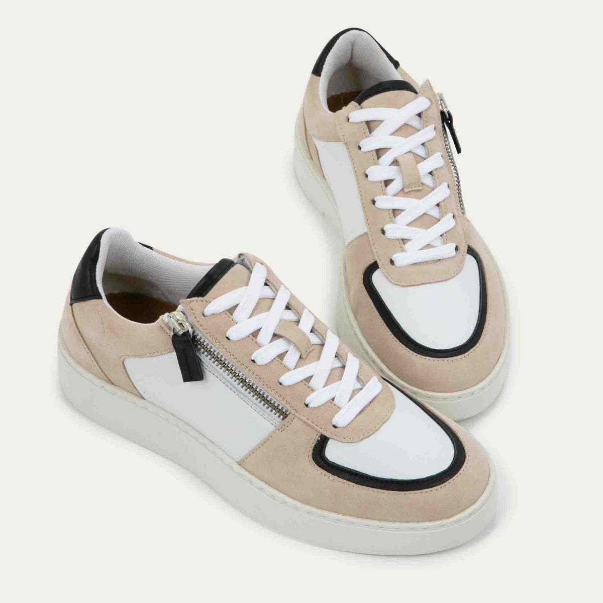 Pair of multicolored white, beige, and black sneakers with laces and a side zipper.
