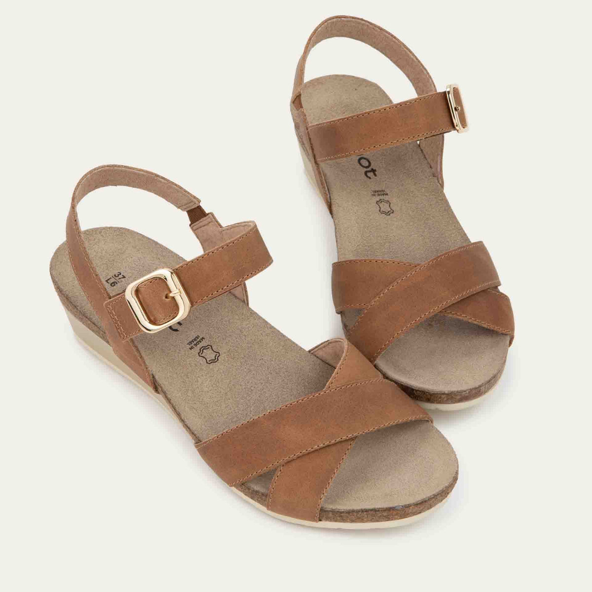 Pair of cork footbed, brown wedge sandals with cross straps and a gold buckle on the ankle strap.