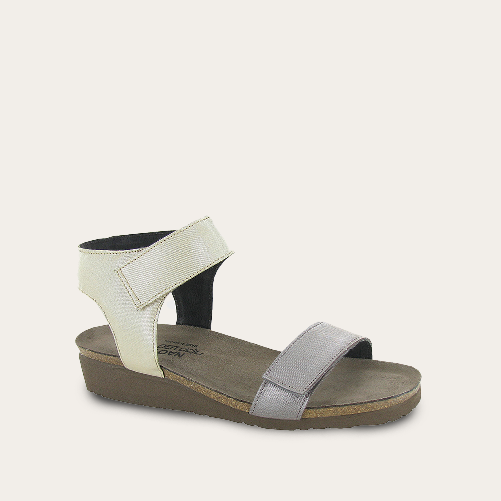 A metallic silver sandal with two adjustable straps and a brown cork sole
