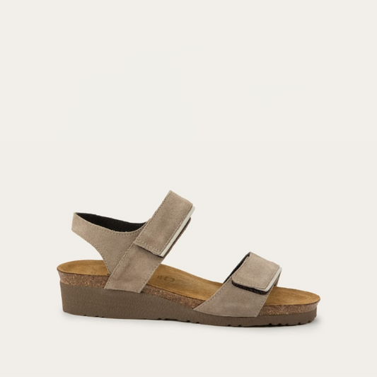 A side view of a beige suede sandal with a cork platform sole.