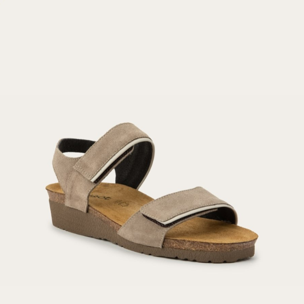 A side view of a beige suede sandal with a cork platform sole.