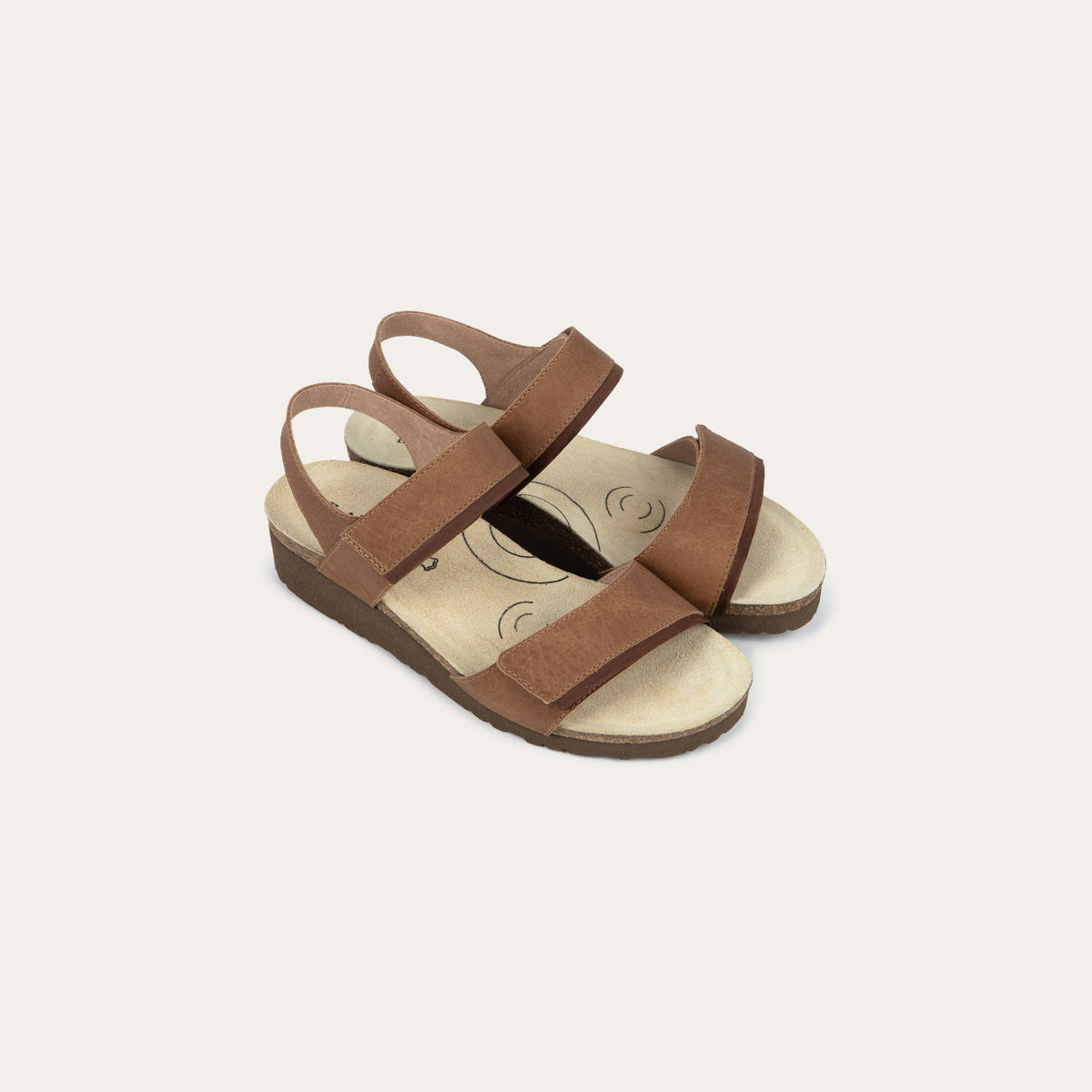 A pair of brown leather sandals with two adjustable straps and a cork platform sole.