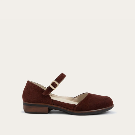 Profile view of a red maryjane with a simple buckle strap on a black and brown sole