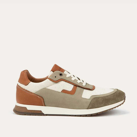 Profile view of a green and beige sneaker featuring different materials on a white sole