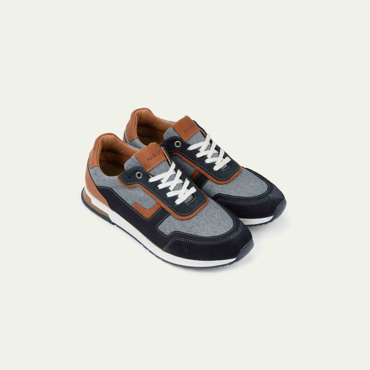 Pair of  blue and brown sneakers featuring different materials on a white sole