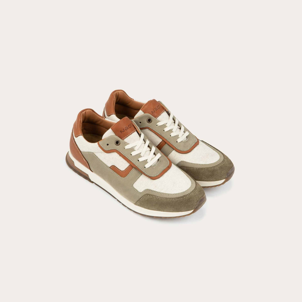 Pair of  green and beige sneakers featuring different materials on a white sole