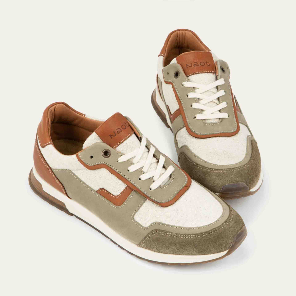 Pair of  green and beige sneakers featuring different materials on a white sole