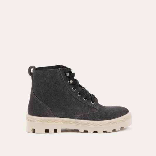 Profile view of a black textured suede high-top boot with black laces and a light beige sole. 