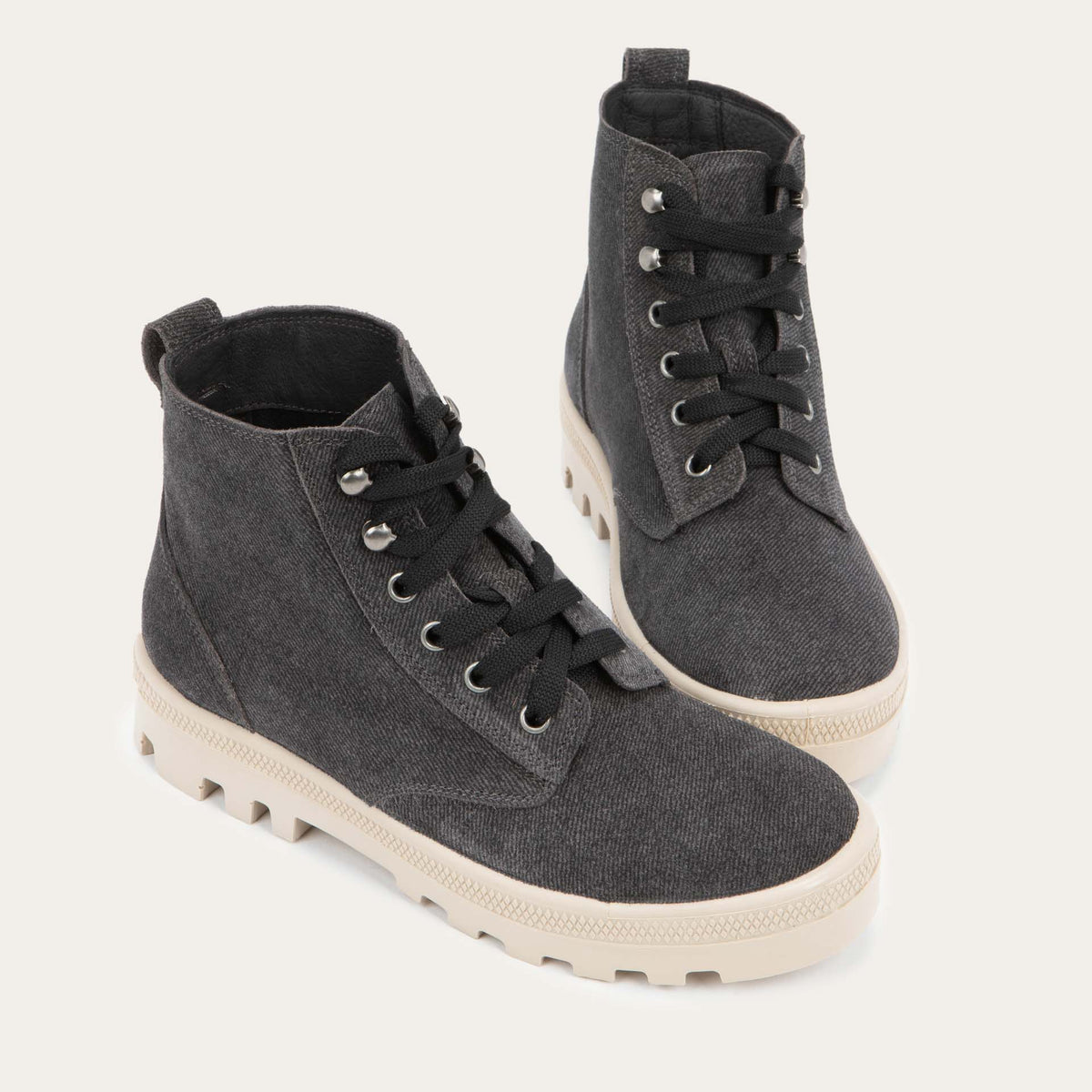 Pair of  black textured suede high-top boots with black laces and a light beige sole. 