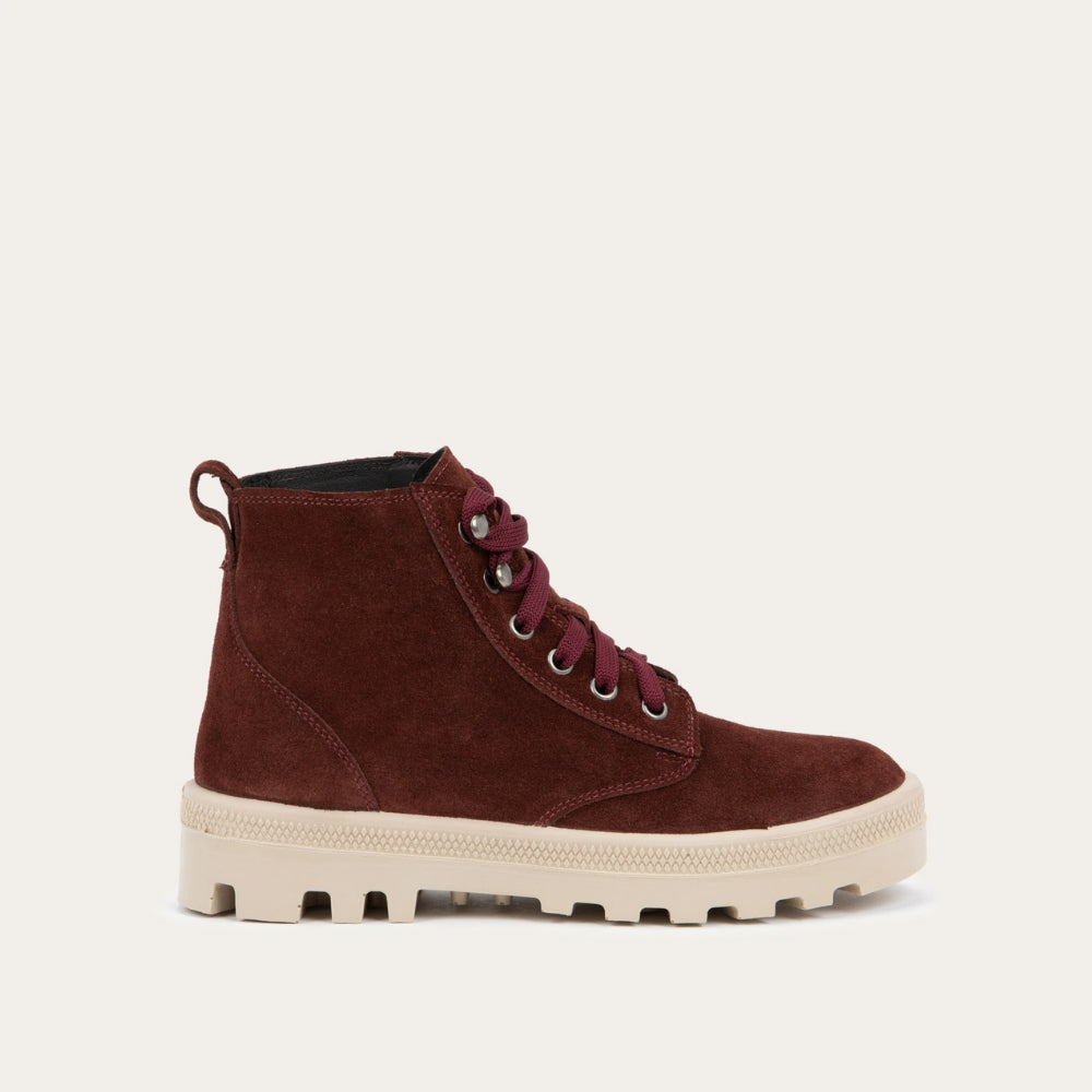 Profile view of a violet textured suede high-top boot with violet laces and a light beige sole. 