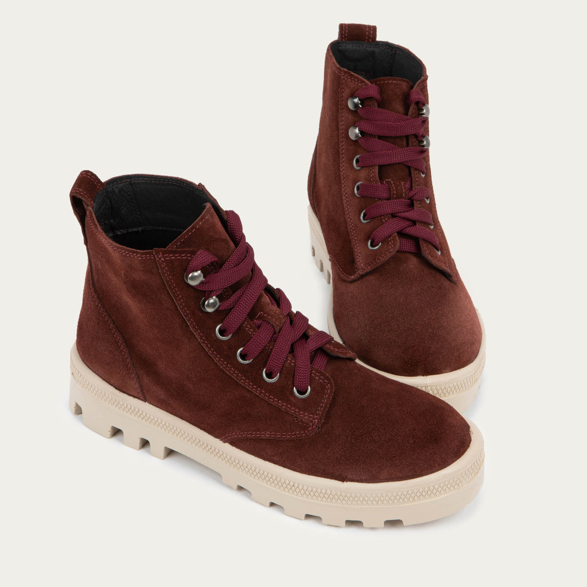 Pair of  violet textured suede high-top boots with violet laces and a light beige sole. 