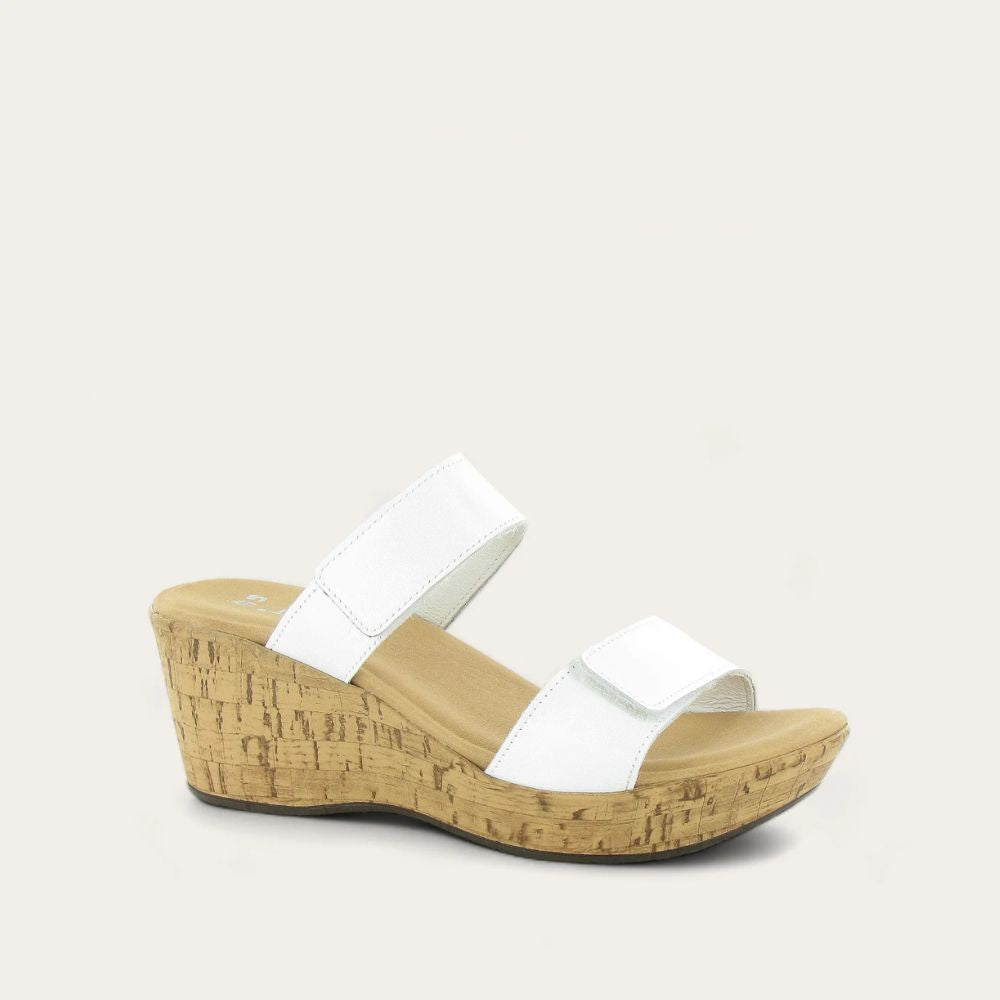 A white, adjustable wedge sandal with two hook and loop straps and a cork sole.