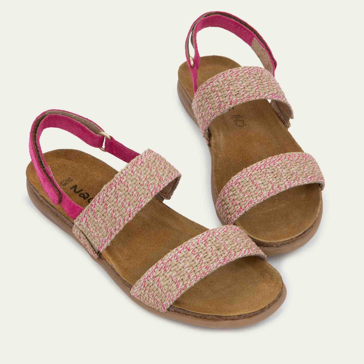 Pair of  pink sandals featuring two textured toe straps and an adjustable ankle strap on a cork footbed.