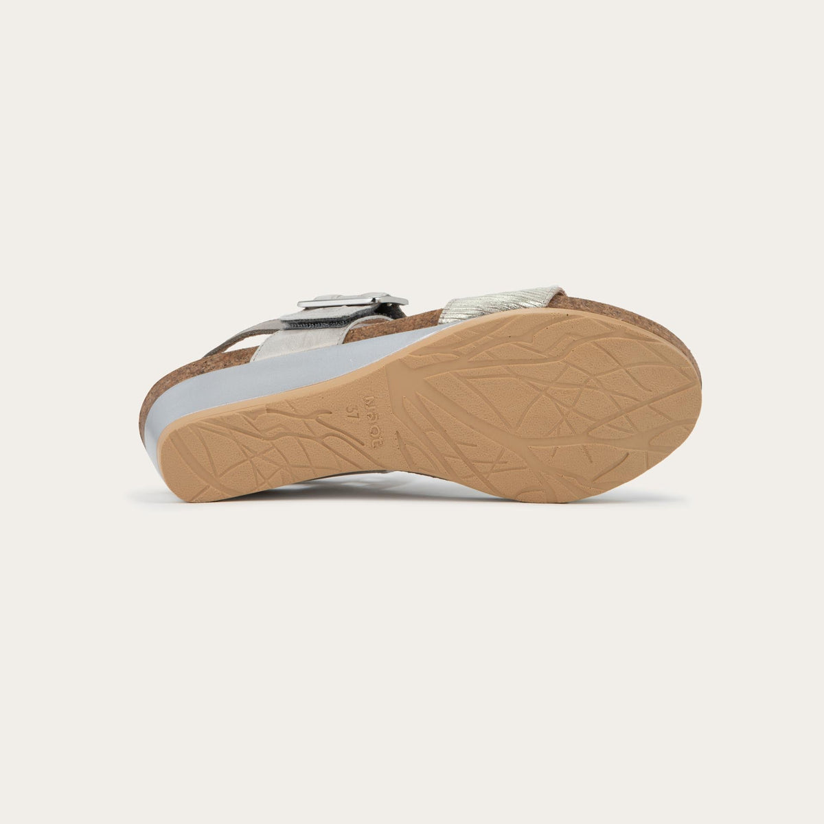 Bottom view of a grey/beige metalic wedge sandal, featuring two straps and a metallic buckle with a cork footbed.