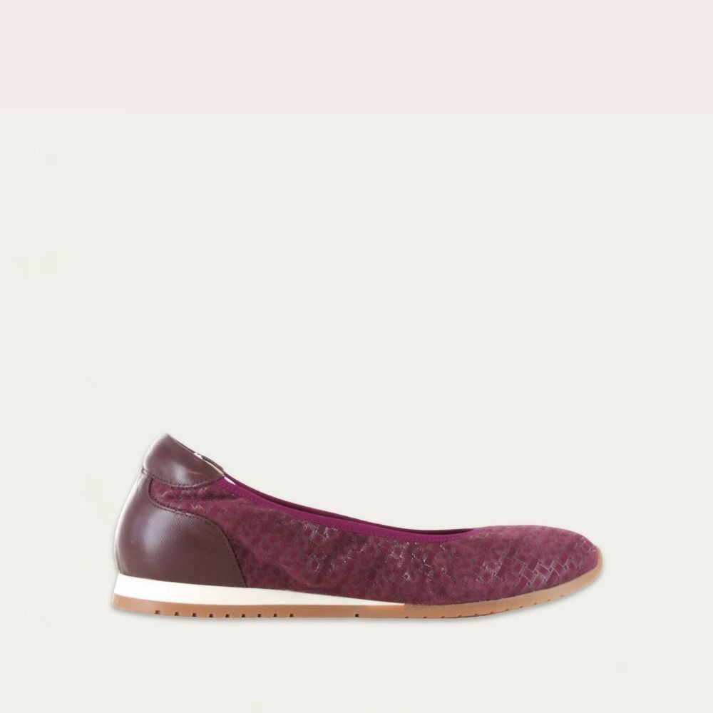 Profile view of a textured purple suede flat on a low white and beige sole. 