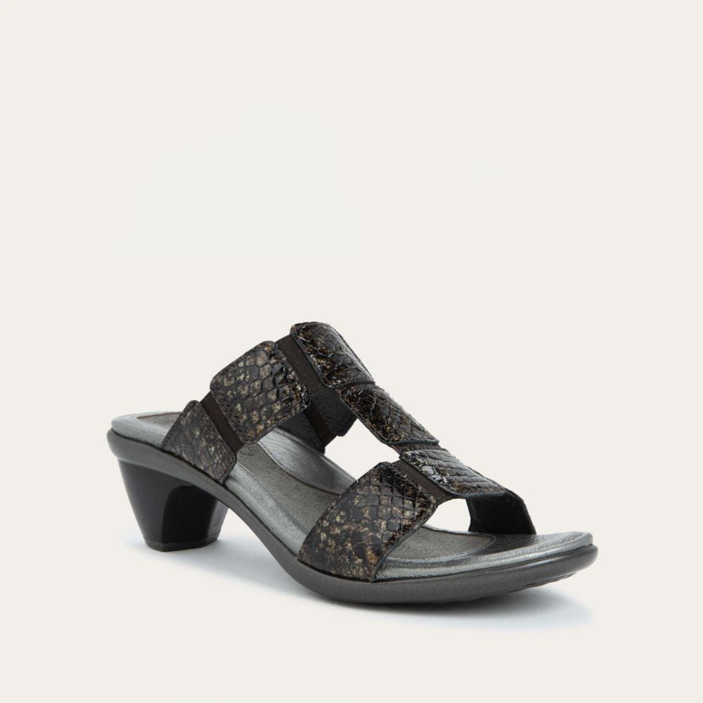 Angled profile view of a slip-on t-strap reptile printed sandal with a mid-height heel .