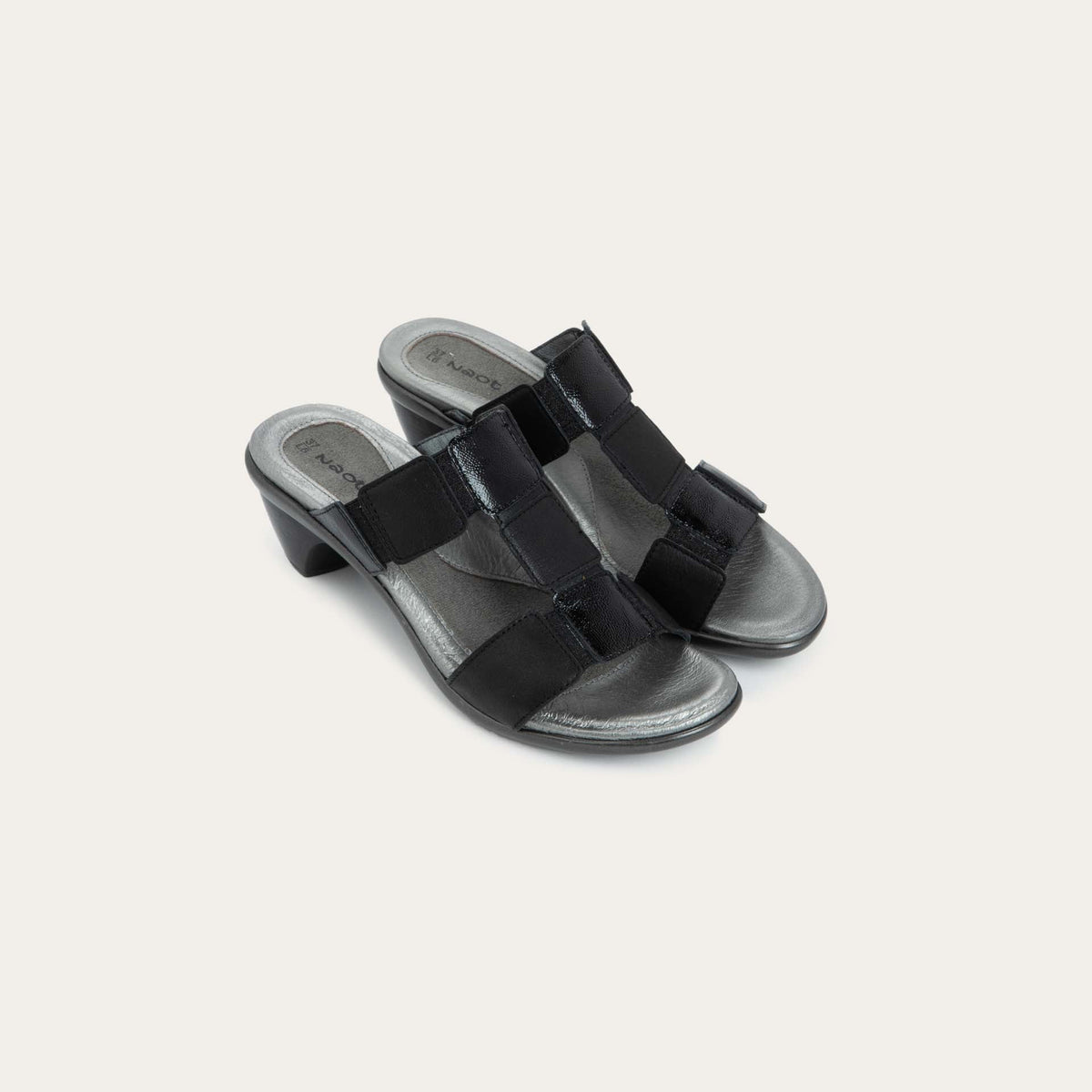 A pair of slip-on t-strap black sandals with a mid-height heel .
