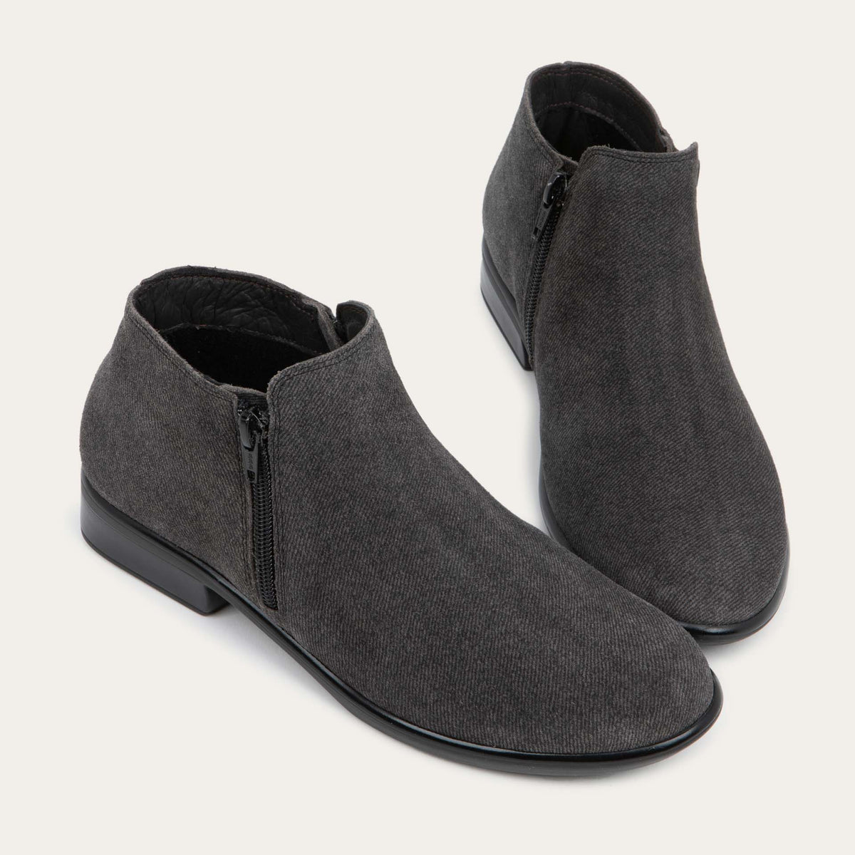 A pair of black suede booties on a black and brown sole.
