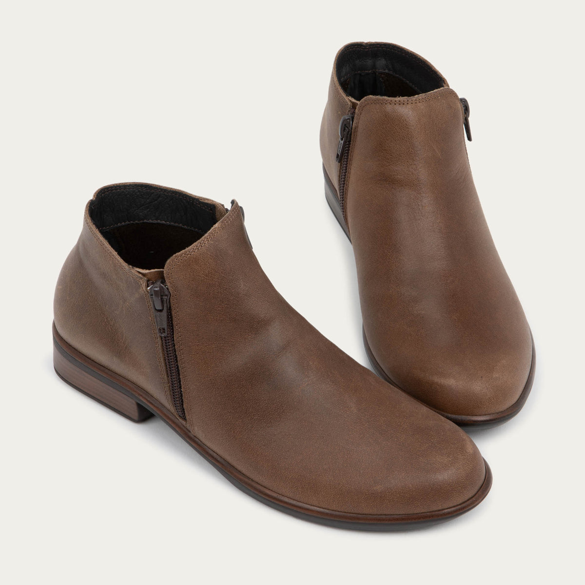 A pair of a brown booties with a black and brown sole.