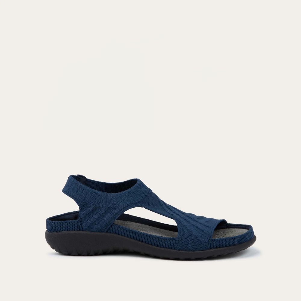 Profile view of a navy knit cutout sandal with open toes, elastic ankle strap, and black textured sole.