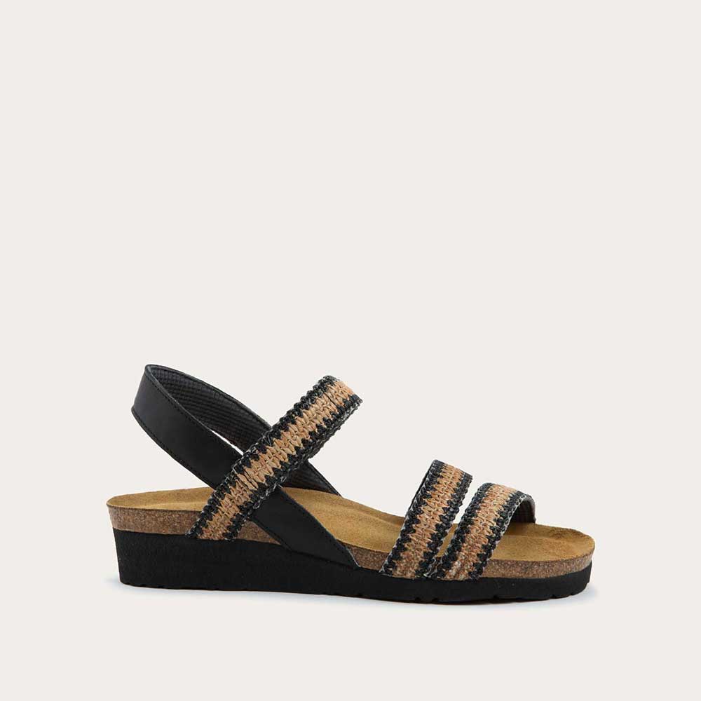 Profile view of black and brown raffia sandal with a cork footbed, black sole, and triple-strap design including a crisscross ankle strap.