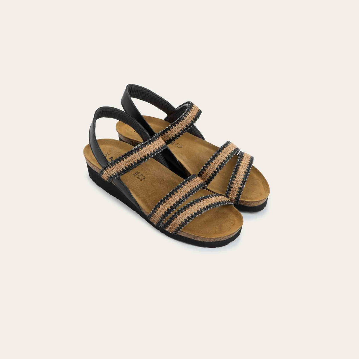 View of a pair of black and brown raffia sandals with a cork footbed, black sole, and triple-strap design including a crisscross ankle strap.