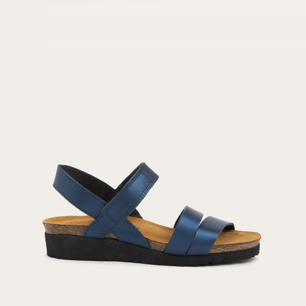 Profile view of a navy blue sandal with a cork footbed, black sole, and triple-strap design including a crisscross ankle strap.