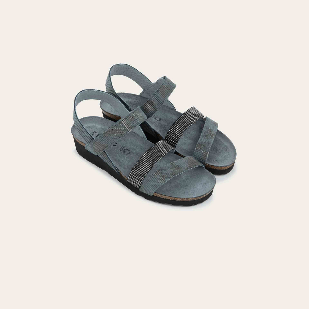 A pair of  gray sandals with two textured straps and a studded strap on a cork and black rubber sole,