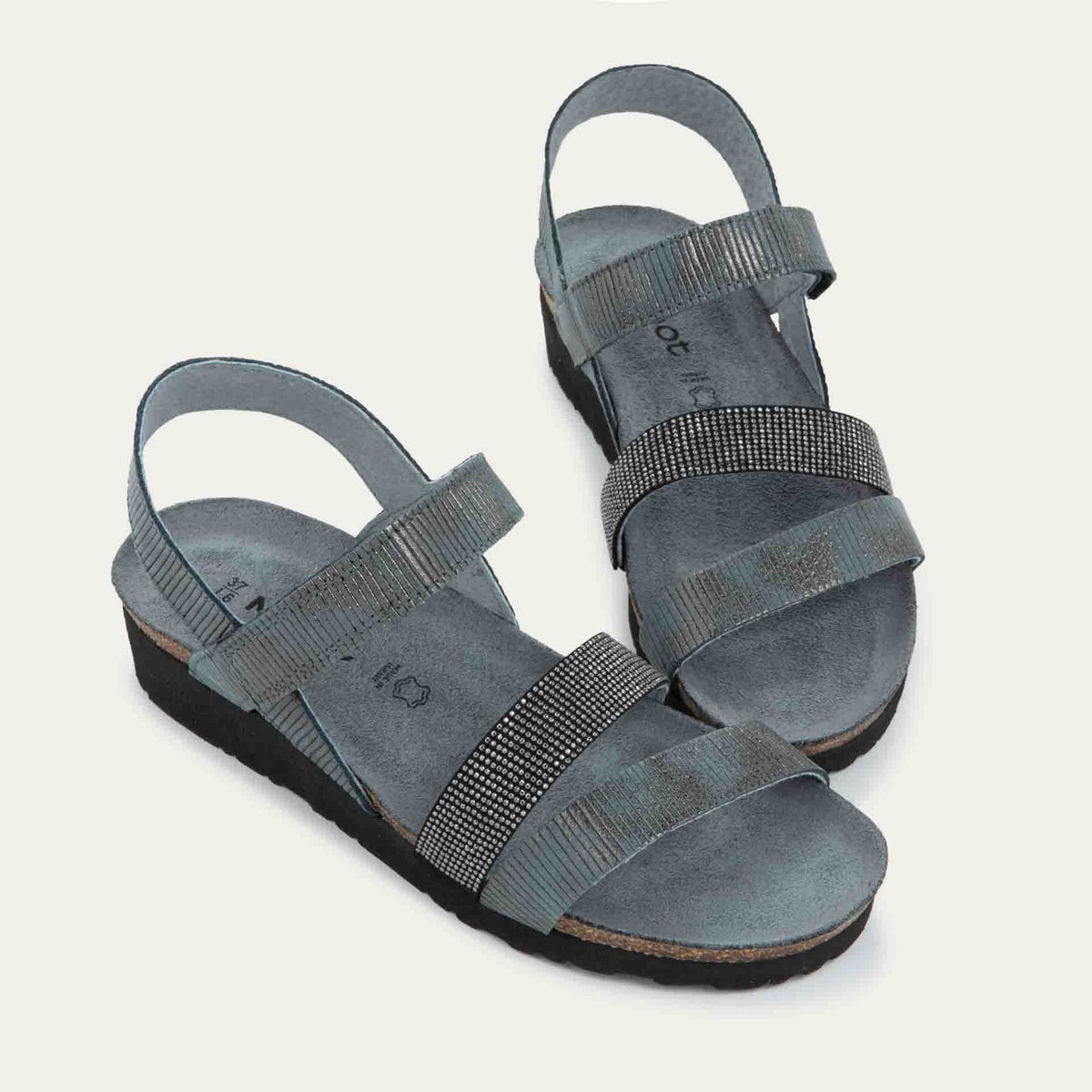 A pair of  gray sandals with two textured straps and a studded strap on a cork and black rubber sole,