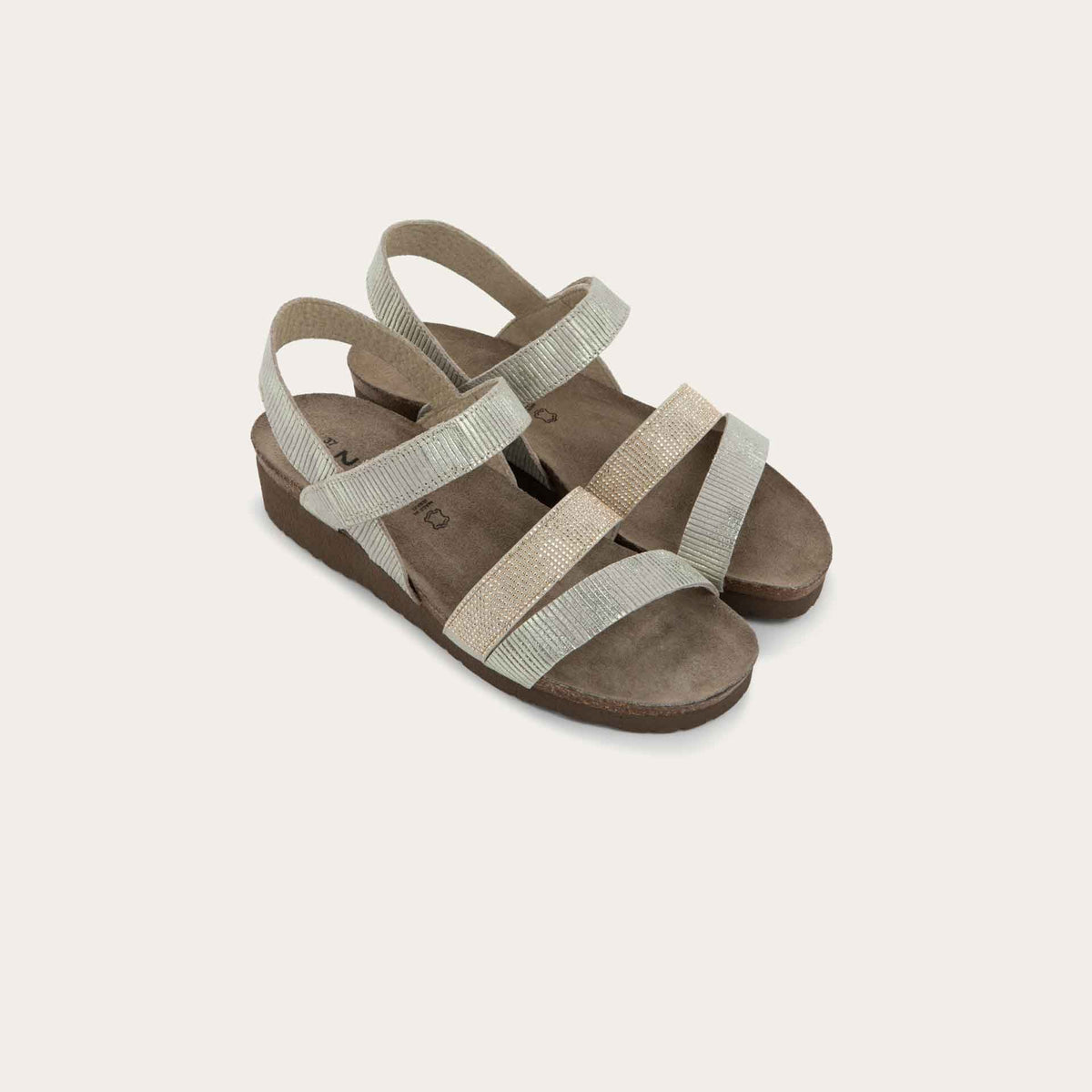 A pair of  beige sandals with two textured straps and a studded strap on a cork and black rubber sole,