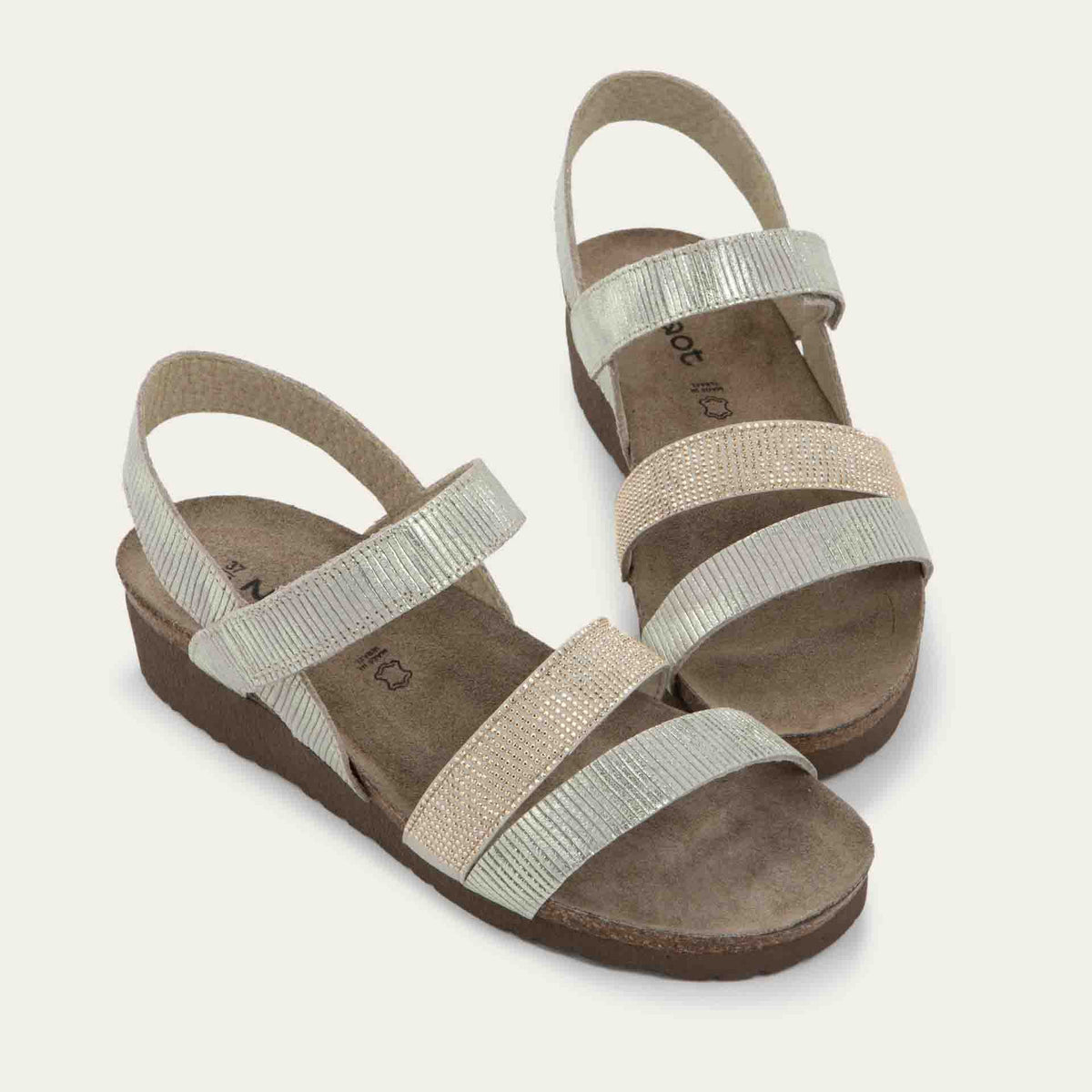 A pair of  beige sandals with two textured straps and a studded strap on a cork and black rubber sole,