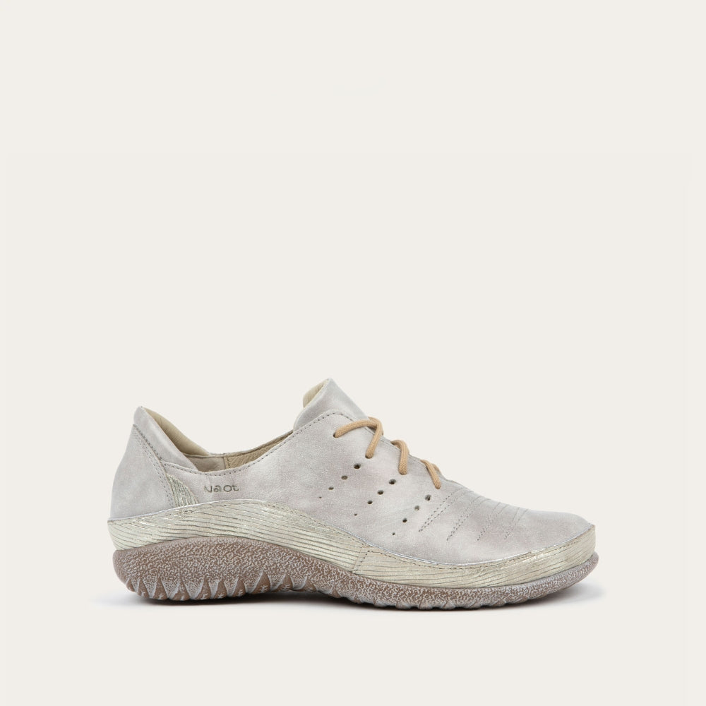 Profile view of a casual beige lace-up shoe with textured sole and side perforations.