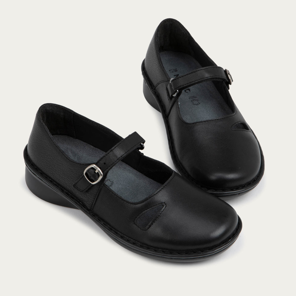 Pair of  black maryjanes on a black sole featuring a simple buckle and small cutout detail on the side