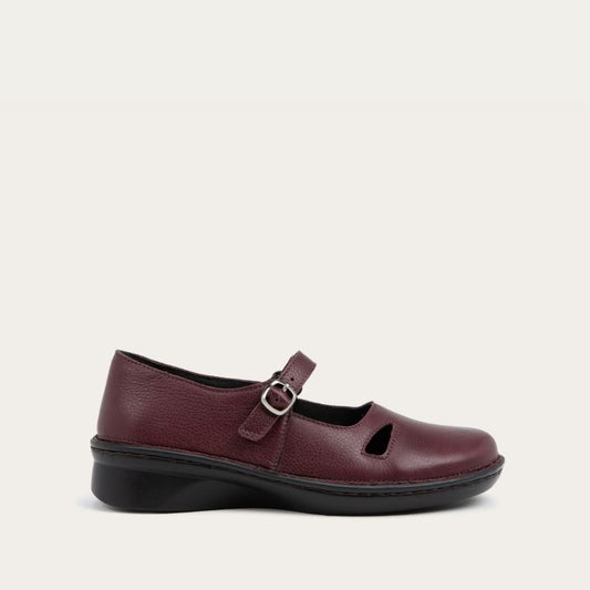 Profile view of a red maryjane on a black sole featuring a simple buckle and small cutout detail on the side