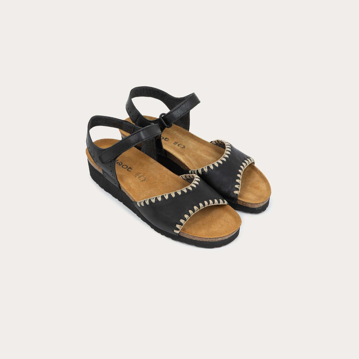 View of a pair of black and brown raffia sandals with a cork footbed, black sole, and triple-strap design including a crisscross ankle strap.