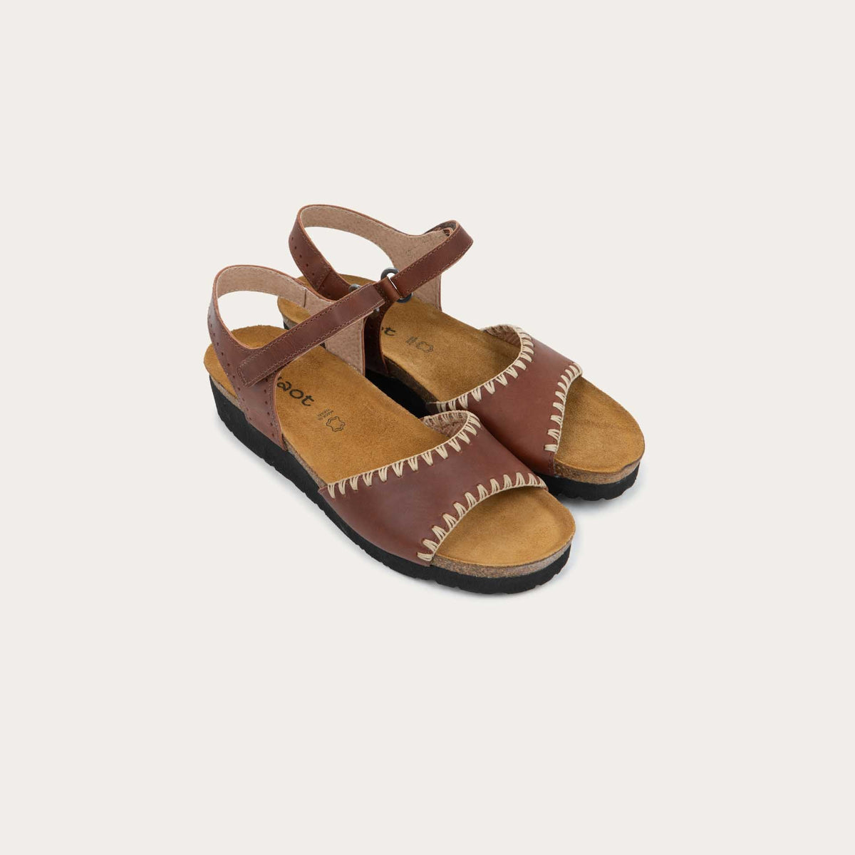 Pair of brown sandals featuring a toe strap with contrast stitiching, adjustable ankle strap, and a cork footbed.
