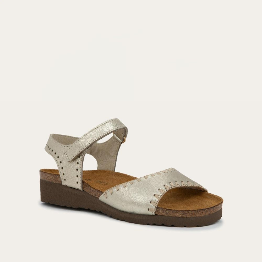 Angled profile view of a gold sandal featuring a toe strap with contrast stitiching, adjustable ankle strap, and a cork footbed.