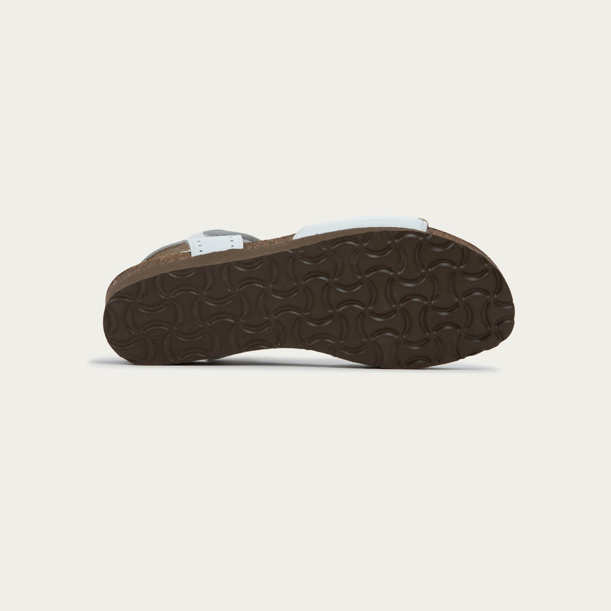 Bottom view of a white sandal featuring a toe strap with contrast stitiching, adjustable ankle strap, and a cork footbed.