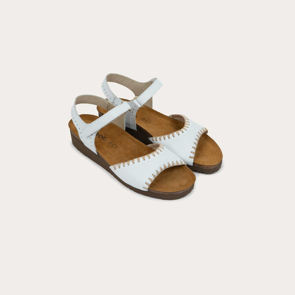 Pair of white sandals featuring a toe strap with contrast stitiching, adjustable ankle strap, and a cork footbed.