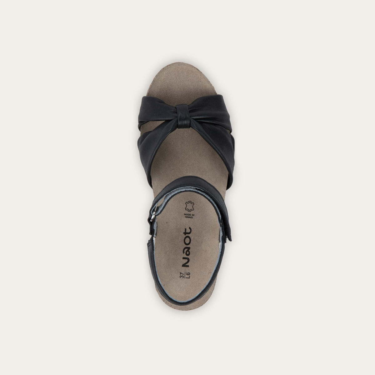 Top view of a black wedge sandal with an ankle strap and twisted front strap, featuring a cork footbed and wedge heel. 