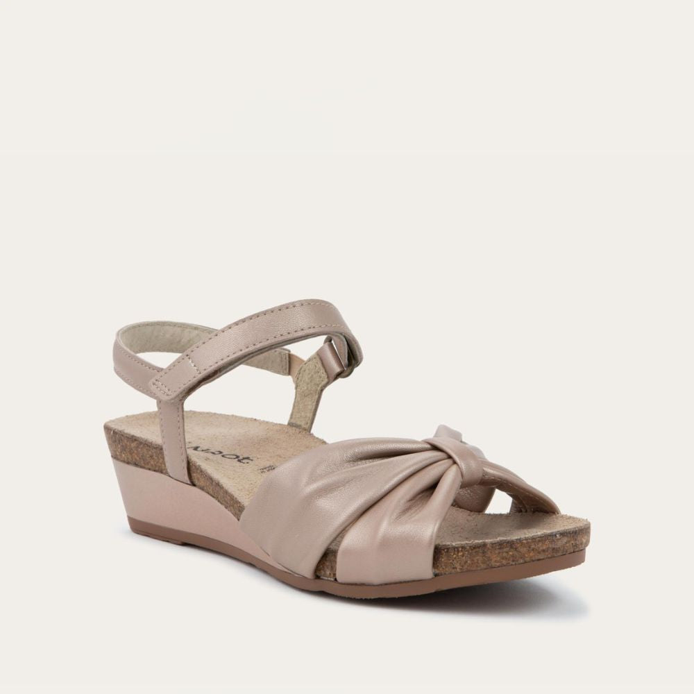 Angled profile view of a mauve wedge sandal with an ankle strap and twisted front strap, featuring a cork footbed and wedge heel. 