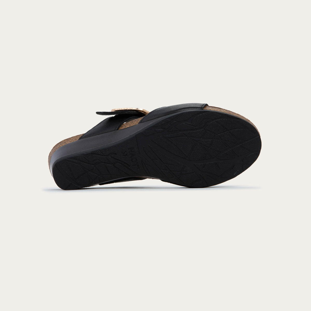 Bottom view of a black slip-on wedge sandal with two straps and a large textured buckle.  