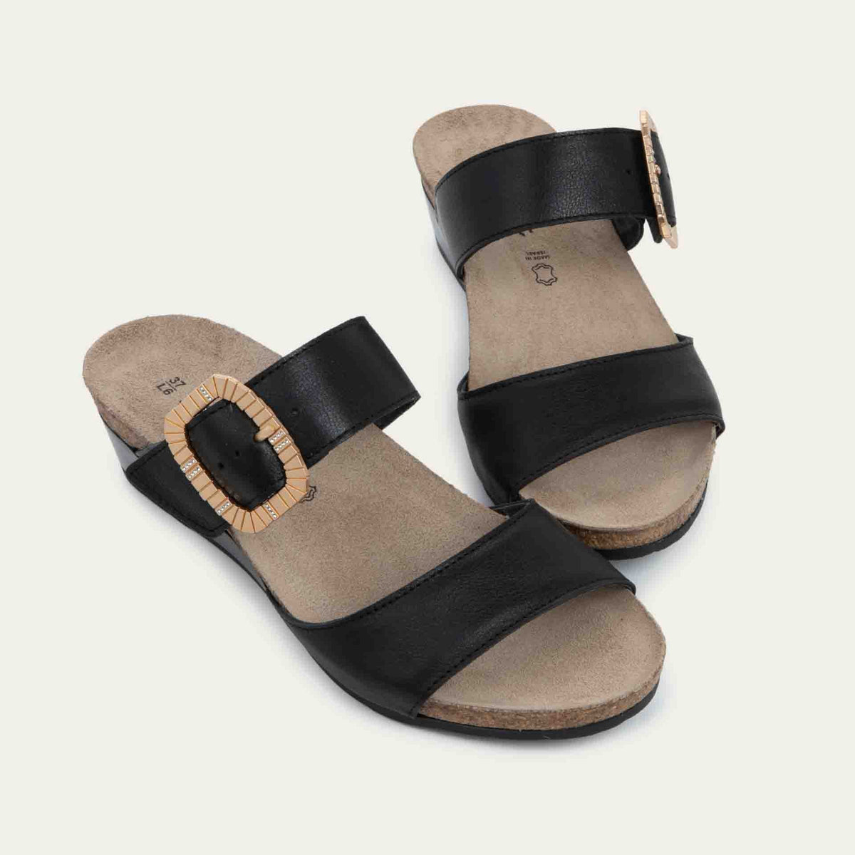 Pair of black slip-on wedge sandals with two straps and a large textured buckle. 
