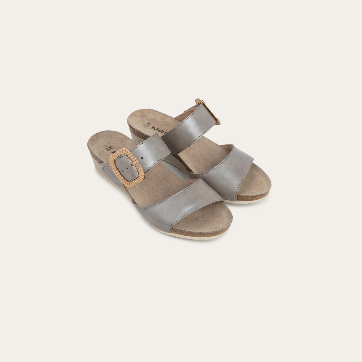 Pair of metalic gray slip-on wedge sandals with two straps and a large textured buckle. 