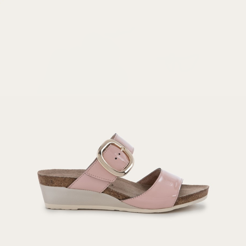 A pink sandal with an oversized buckle and a low wedge heel.