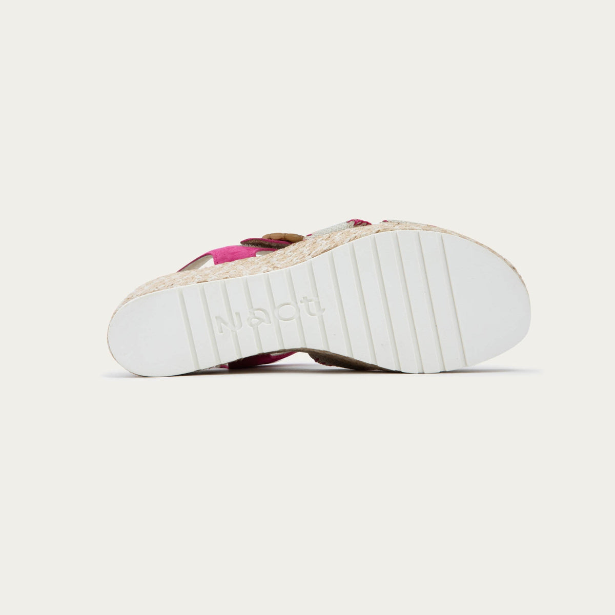 Bottom view of a beige/pink wedge sandal with a woven platform and pink suede ankle strap, fastened by a circular buckle. 